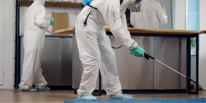 Profissionais com trajes de proteção aplicando desinfetante, vestindo tecidos com acabamento antibacteriano para ambientes controlados